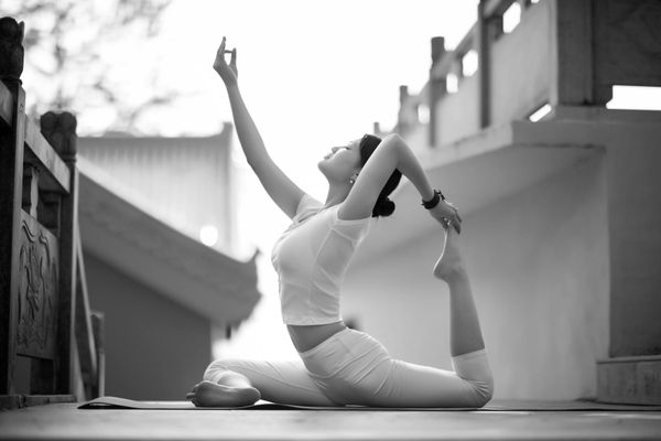 Person stretching deeply in a peaceful outdoor setting at sunrise.