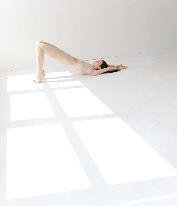 Woman in a serene yoga pose in a bright, minimalist studio.